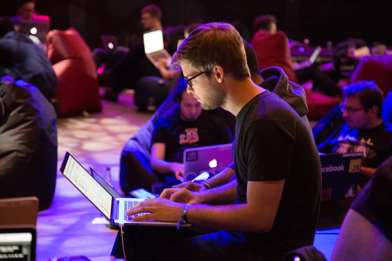 Young talented programmers sitting in a room and coding using powerful laptops.