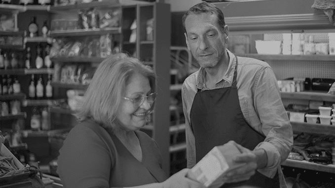 A seller helps the buyer choose a product in a retail shop.