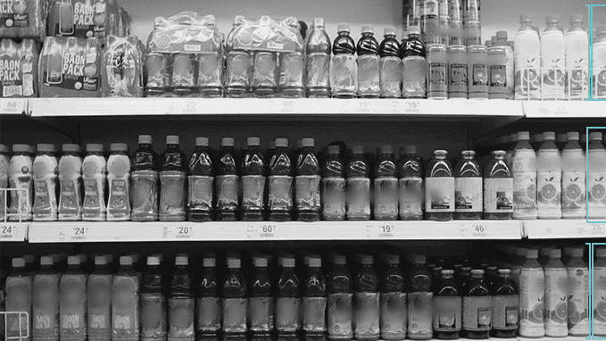 A greyscale image of juice bottles on the shelf of a supermarket.