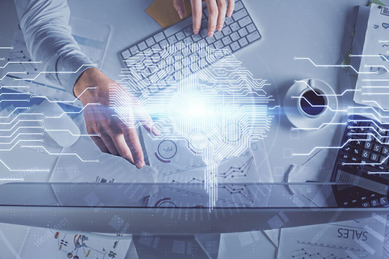 A person working on a computer with a diagram of a futuristic AI interface projected in front.